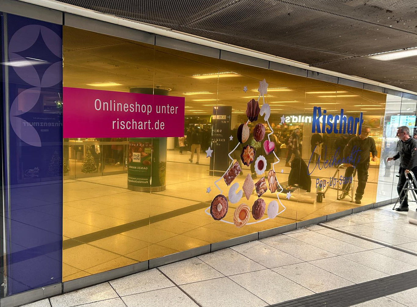Person installing a decorative glass panel with food images on a store front.